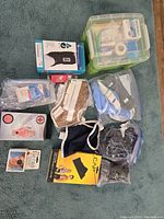 Overview photo of the box first aid kit and various braces, slings, and first aid supplies arranged on carpet