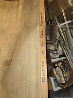 Photo showing a close-up of the wooden border/frame of the wall hanging with handwritten title 'Diagram of the Great Pyramid'. Surrounding area shows storage or garage items for scale.