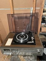 Calibron vintage record player with dust cover, manual document on side, wood finish and control knobs visible