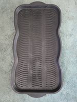 Top-down view of a single black rubber boot tray showing textured interior pattern and shape