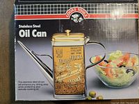 Box of the stainless steel oil can showing branding and product image.