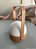 Front view of the battery operated lantern showing the tan handle and base with white dome light cover.