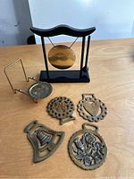 Photo showing all items in the lot including the gong on stand, cup and plate holder, and four brass medallions with various designs
