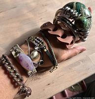 Display of eight costume jewelry bracelets and bangles on a wrist showing their fit and style.