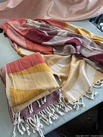 Two large cotton Turkish towels laid on a surface showing mixed warm colors, woven texture, and knotted fringe ends.