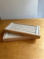 Two stacked wooden ring holder trays showing soft cushioned ring slots inside one tray.