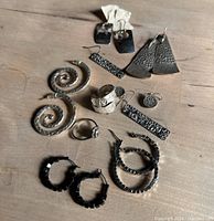 Photo showing all 7 sets of earrings and 2 rings on a wooden surface.