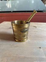 Small brass mortar with horizontal decorative ridges and dark tarnish spot on exterior, showing wear.