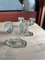 Two vintage style heavy glass candle holders with a ribbed vertical pattern and octagonal base, photographed from front and side angles on a wooden surface.