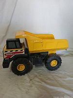 Side angle showing yellow body, cargo bed, and large rubber wheels with yellow rims.