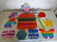 Photo showing all nine assorted Pop Its fidget toys including hamburger, star, butterfly, unicorn, hexagon, square, and Santa hat shapes.