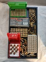 Various brass casings, some loaded rounds in green and red plastic holders on black tray