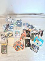 Various sports cards spread on surface including football, basketball, and baseball cards, some in sleeves and others loose.