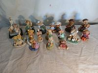Overview of 14 ceramic figurines including bears and rabbits arranged on a surface in two rows.