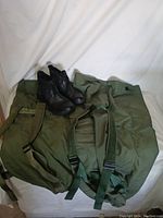 Photo showing two olive green duffel bags and one pair of black 5.11 tactical boots size 11 arranged on a white background.