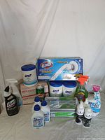 Full view of assortment of home cleaning supplies including wipes, spray bottles, power scrub brush, and other cleaners.