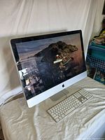 Front angle view of Apple iMac desktop computer powered on, showing login screen with coastal island background.