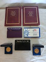 Overview of coin proof sets and binders including two red binders labeled for Indian Head Pennies and Buffalo Nickels, United States Mint proof sets from 1992, 2005 and 1978, and two blue cases with gold coins.