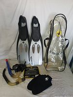 Full set of snorkeling gear including fins, gloves, snorkels, mask and carrying case arranged on a white surface