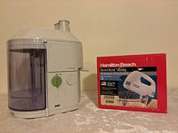 Braun electric juicer beside Hamilton Beach hand mixer box on table