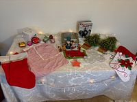 Overview of the entire lot showing stockings, apron, cookbook, ornaments, cookie tin, greenery, figurines and lights