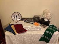 Full overview of all items on fabric-covered table including banners, sign, poster, wigs, scarves, and wands.