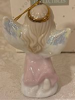 Back view of Avon Precious Memories porcelain angel ornament showing gold halo, pastel pink gown, and white wings with blue accents