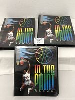 Three black binders titled 'In The Paint' with a basketball player illustration on front covers, standing upright showing front covers.