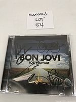 Front of the CD jewel case with Bon Jovi Lost Highway cover featuring multiple autographs in black marker