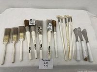 Full view of all brushes and knives in the set on white background with lot label.