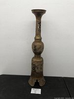 Full frontal view of tall brass candle holder showing overall shape and base