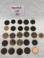 Front view of twenty-three assorted coins laid out on white fabric with a label showing LOT 26