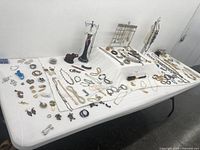 Wide view of a table with an assortment of costume jewelry items including necklaces, bracelets, earrings, rings, brooches, and display holders.
