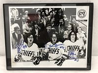 Full image of the framed black and white photo showing all three Hanson Brothers in Chiefs hockey jerseys, signed in blue marker.