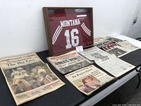Framed jersey and newspaper clippings laid out on table, front view