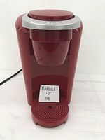 Front view of the red Keurig coffee maker showing the drip tray and front profile.