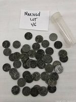 Photo showing all 50 Lincoln Wheat pennies scattered next to a clear plastic coin tube and a paper note with lot number.