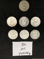 Top view of seven Mexican silver coins arranged on black background, showing obverse designs with portraits and emblems.