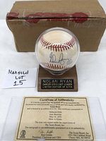 Front view of Nolan Ryan autographed baseball in protective display case with wooden base and engraved plaque, certificate of authenticity and shipping box in background.