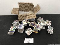 Overhead photo of a USPS box filled with multiple stacks of sports cards and several loose stacks spread out on a black table.