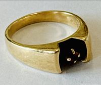 Front view of gold ring showing recessed round gemstone and split-shoulder design on neutral background
