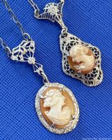 Close-up of two cameo pendants showing shell carvings and filigree settings.