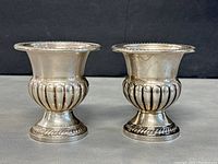 Pair of vintage sterling silver toothpick holders shown side by side on black background, showing detailed shape and rope edge design.