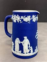 Front side of Wedgwood jasperware pitcher showing grapevine and classical figures in white relief