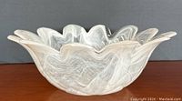 Side view showing the white swirled Murano glass bowl's wavy scalloped edge and translucent glass.