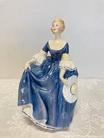 Front view of Royal Doulton HN2335 Hilary figurine showing seated woman in blue dress holding hat.