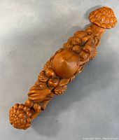 Top-down view of the full length of the carved boxwood ruyi with monkeys and peach motif showing the smooth finish and rounded ends.