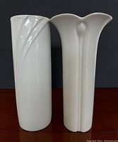 Front view of both white glaze vases, showing cylindrical Hutschenreuther vase with leaf relief on left and petal rim Arzberg vase on right.