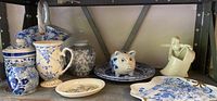 Assorted blue and white china items on shelf including jars, pitchers, plates, and figurines