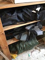 View showing folded black and gray camping chairs with carrying bags, large green tarp beneath.